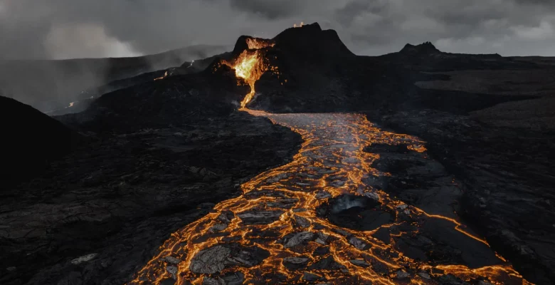 Fluxo de lava incandescente durante uma erupção de um dos vulcões mais impressionantes da natureza em terreno rochoso escuro